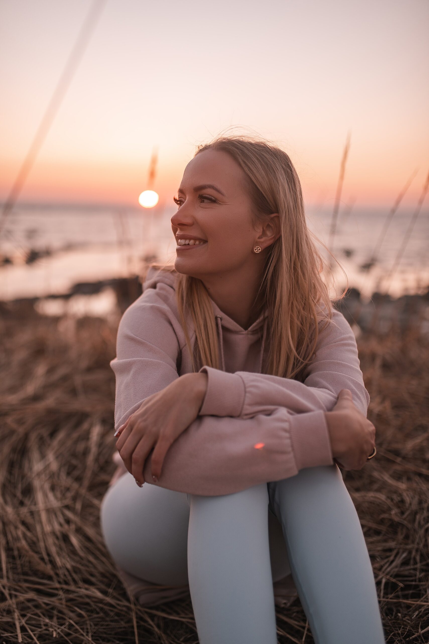Martta Jemina rentoutuu meren rannalla auringonlaskussa